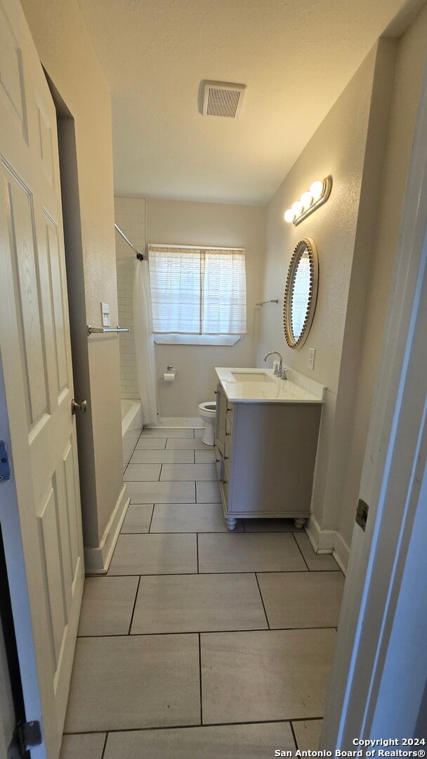 full bathroom featuring tile patterned flooring, vanity, toilet, and shower / bath combo