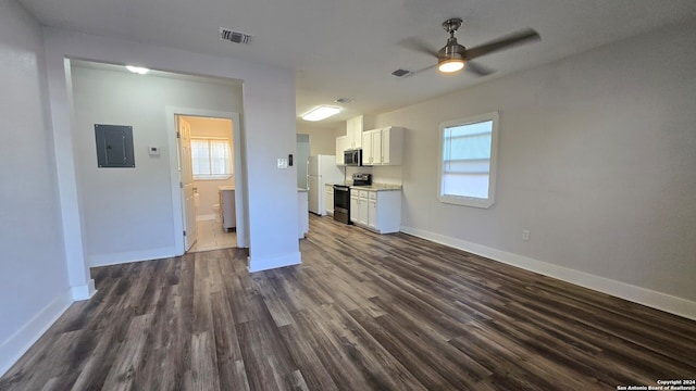 unfurnished living room with ceiling fan, dark hardwood / wood-style floors, electric panel, and a wealth of natural light