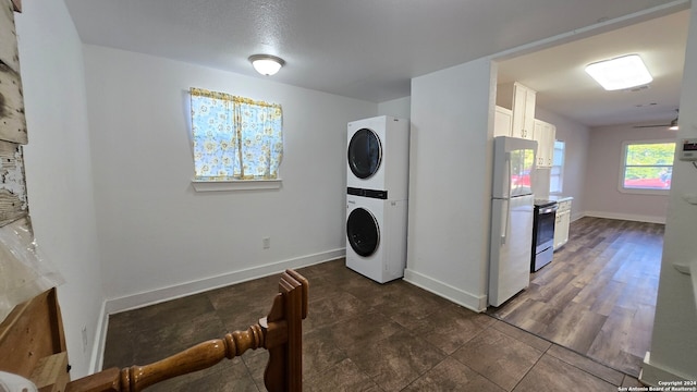 laundry room featuring stacked washing maching and dryer, dark hardwood / wood-style floors, and ceiling fan