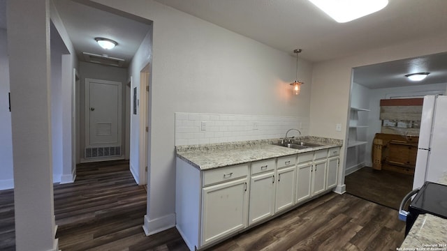 kitchen with sink, white cabinets, dark wood-type flooring, and decorative light fixtures