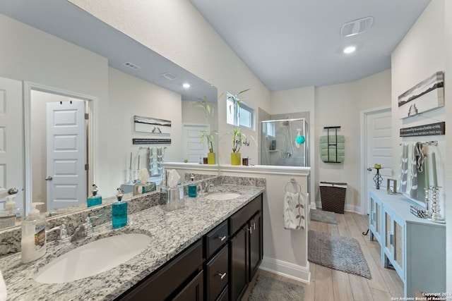 bathroom with hardwood / wood-style floors, vanity, and a shower with door