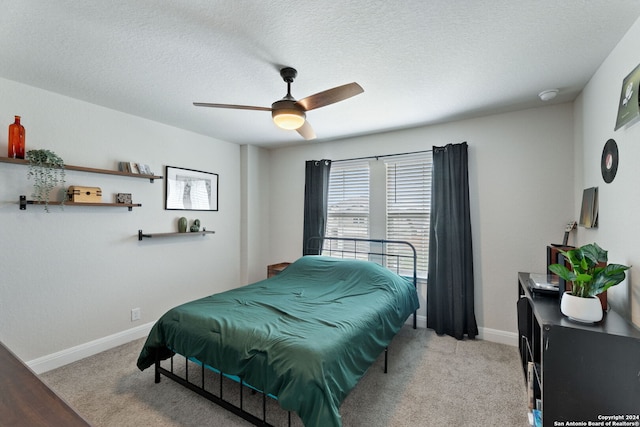 bedroom with ceiling fan, light colored carpet, and a textured ceiling