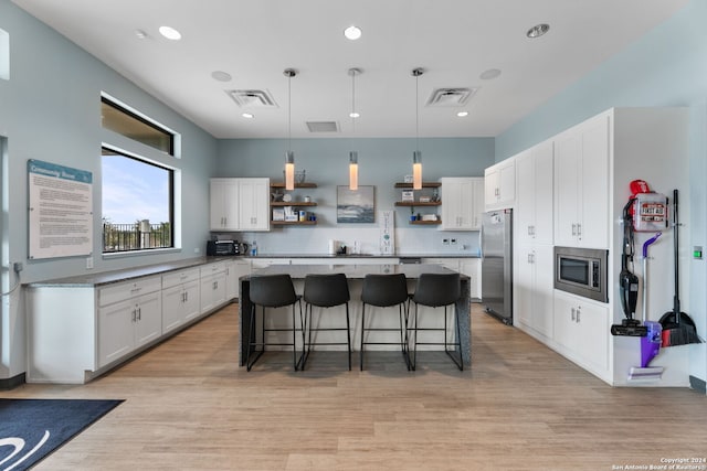 kitchen with a breakfast bar, stainless steel appliances, white cabinetry, and a kitchen island