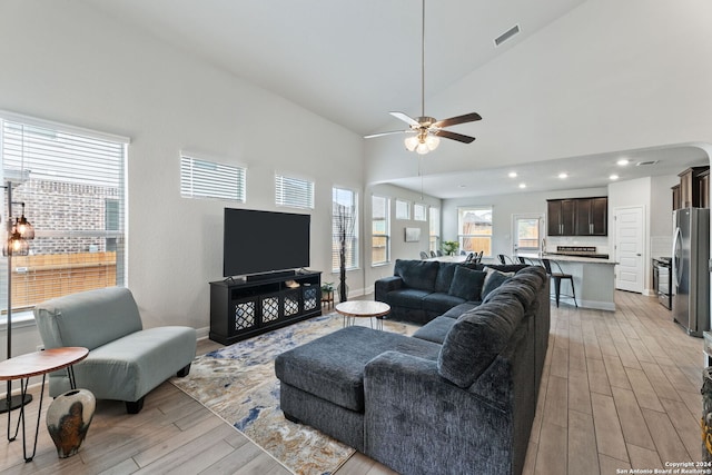 living room with light hardwood / wood-style floors, high vaulted ceiling, and ceiling fan