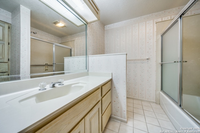 bathroom featuring tile patterned flooring, a textured ceiling, vanity, and bath / shower combo with glass door