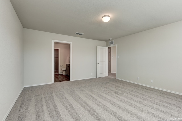 unfurnished bedroom featuring ensuite bath and carpet floors