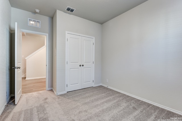 unfurnished bedroom with light carpet and a closet