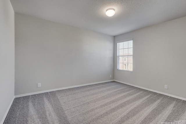 carpeted empty room with a textured ceiling