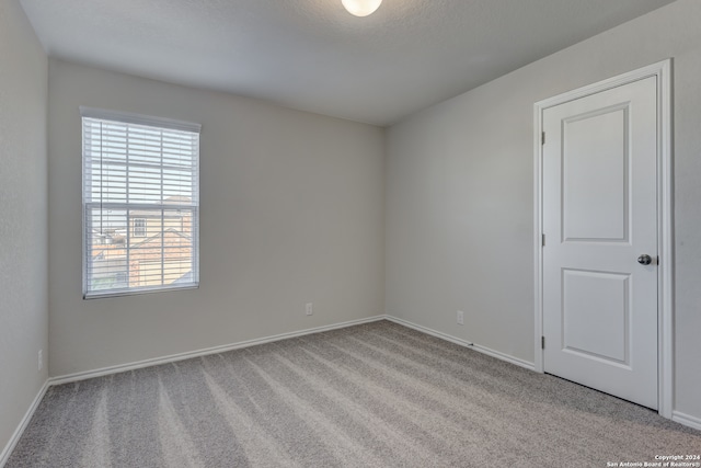 spare room featuring light carpet and a textured ceiling