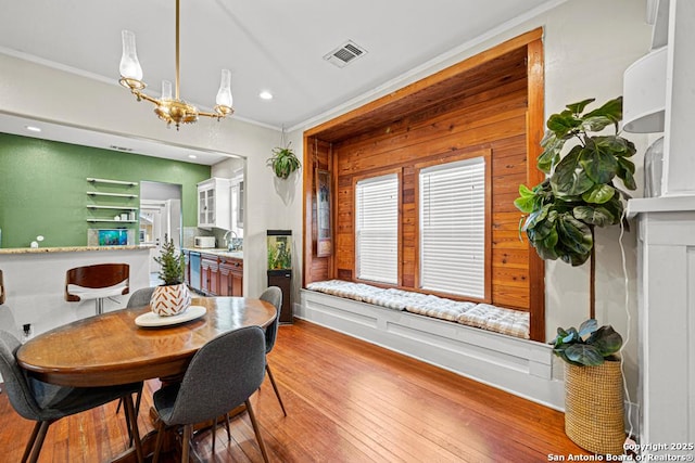 dining space featuring hardwood / wood-style flooring, sink, a chandelier, and ornamental molding