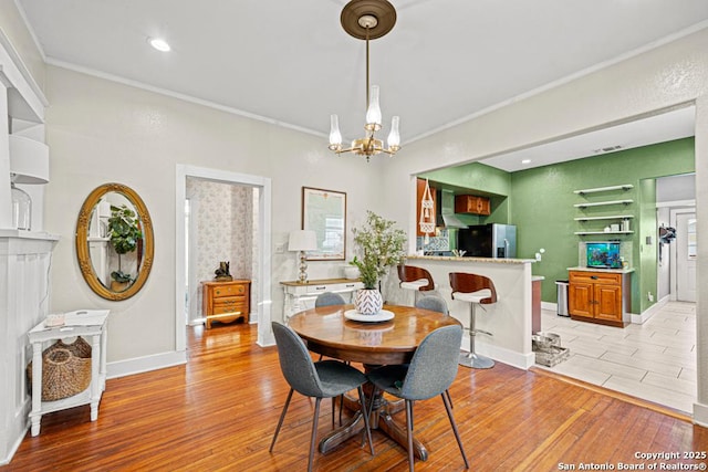 dining area featuring light hardwood / wood-style flooring, a notable chandelier, and crown molding