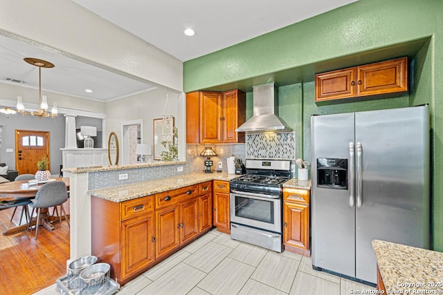 kitchen with kitchen peninsula, appliances with stainless steel finishes, tasteful backsplash, light stone counters, and wall chimney range hood