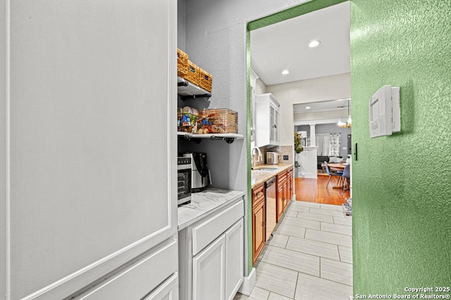 interior space featuring dishwasher, light tile patterned flooring, white cabinetry, and sink