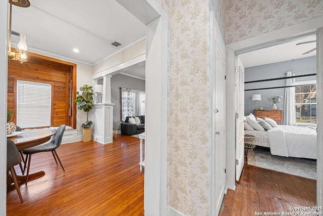 hallway with plenty of natural light, ornamental molding, dark wood-type flooring, and ornate columns