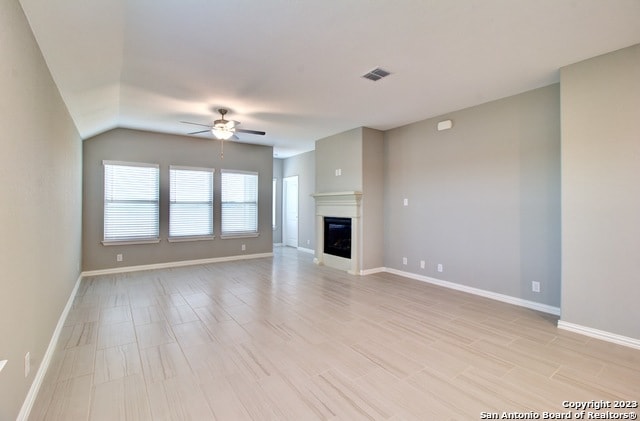 unfurnished living room featuring vaulted ceiling and ceiling fan