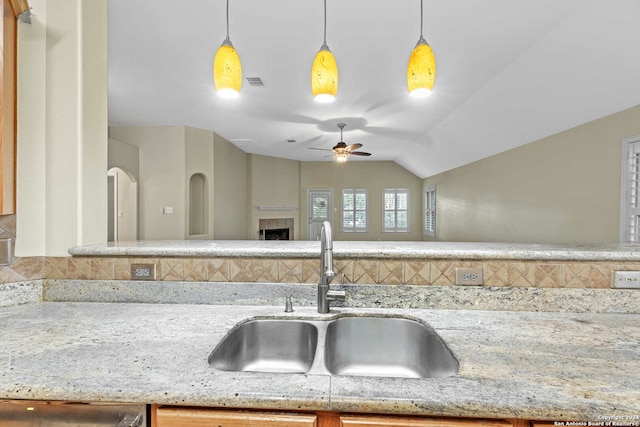 kitchen with decorative light fixtures, vaulted ceiling, ceiling fan, and sink