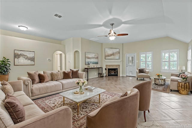 tiled living room with ceiling fan, lofted ceiling, and a tile fireplace