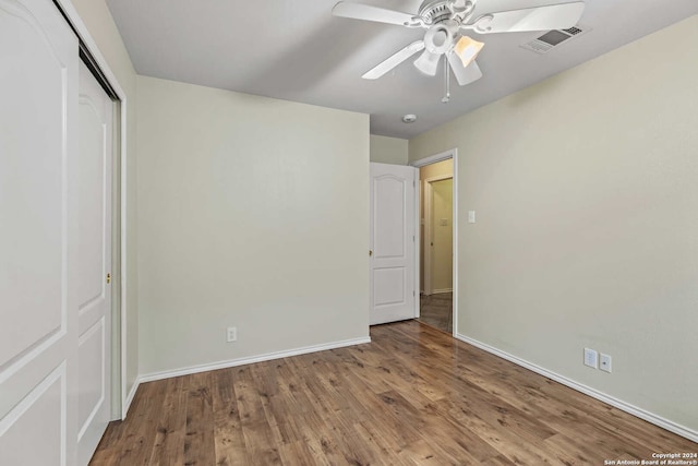 unfurnished bedroom featuring hardwood / wood-style floors, a closet, and ceiling fan