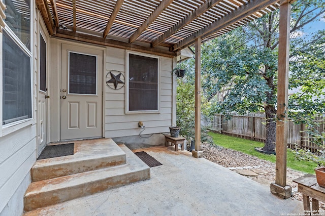 view of exterior entry with a pergola and a patio