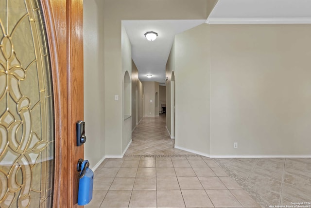 hallway with light tile patterned floors and ornamental molding