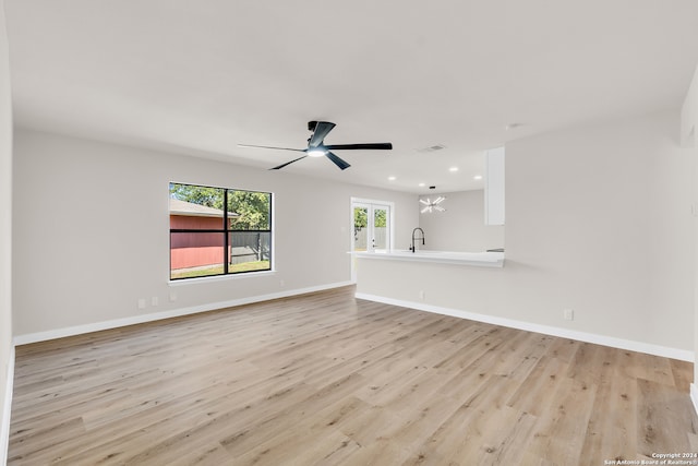 unfurnished living room with ceiling fan, light hardwood / wood-style flooring, and sink