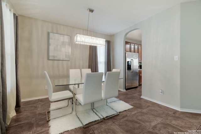 dining space with dark tile patterned floors and a notable chandelier