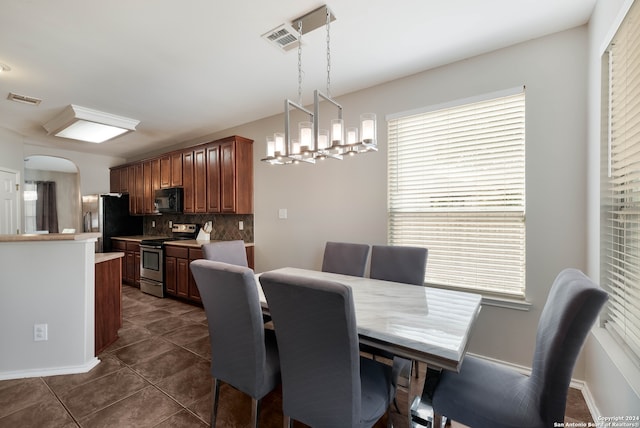 dining space featuring dark tile patterned floors and a notable chandelier