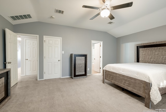 bedroom with ensuite bath, ceiling fan, light colored carpet, and lofted ceiling