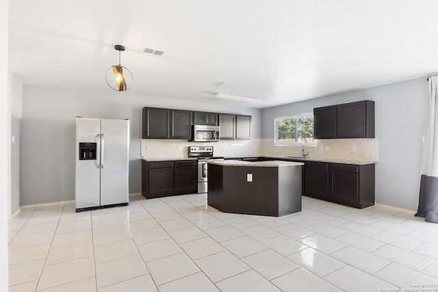 kitchen with appliances with stainless steel finishes, backsplash, light tile patterned floors, pendant lighting, and a kitchen island