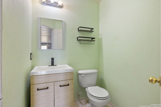 half bathroom featuring toilet, baseboards, and vanity