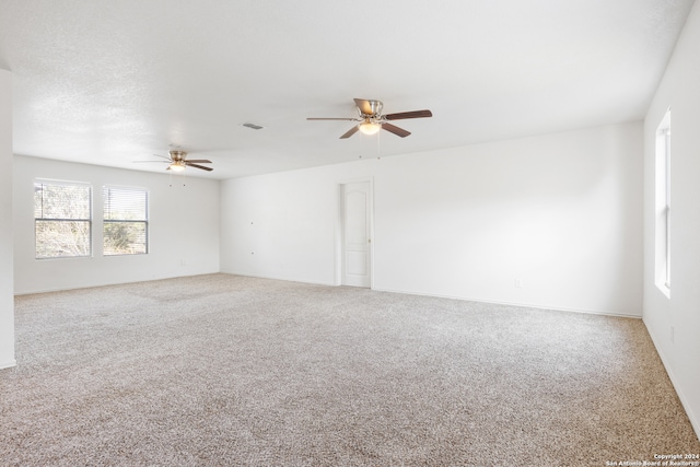 empty room featuring visible vents, carpet flooring, and a ceiling fan