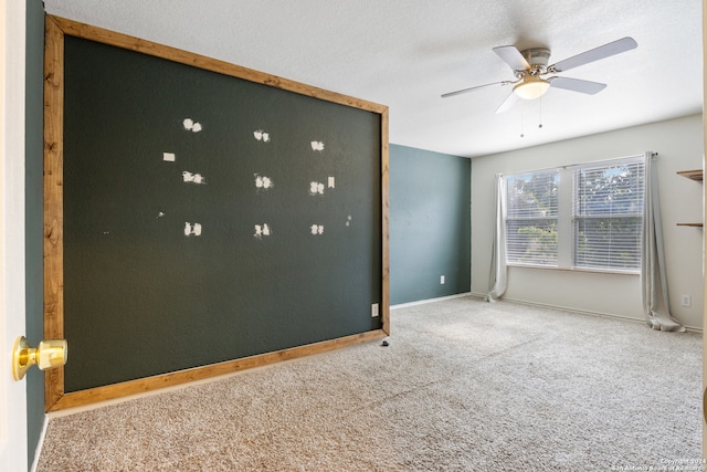 carpeted empty room featuring ceiling fan, baseboards, and a textured ceiling