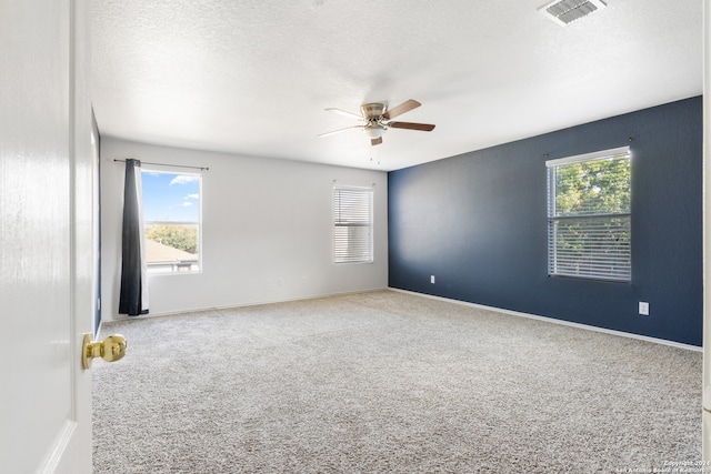 spare room featuring carpet floors, visible vents, ceiling fan, and a textured ceiling