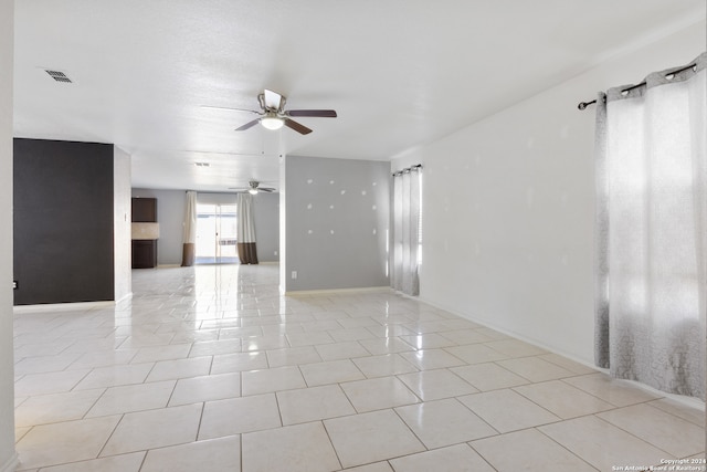 empty room featuring light tile patterned floors, baseboards, visible vents, and a ceiling fan