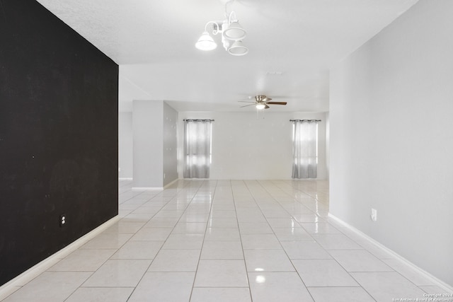 unfurnished room featuring ceiling fan with notable chandelier and light tile patterned floors