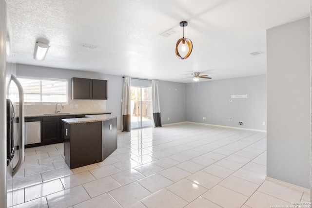 kitchen featuring light tile patterned floors, backsplash, stainless steel dishwasher, a kitchen island, and ceiling fan