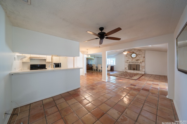 unfurnished living room with ceiling fan, lofted ceiling, a textured ceiling, a fireplace, and light tile patterned floors