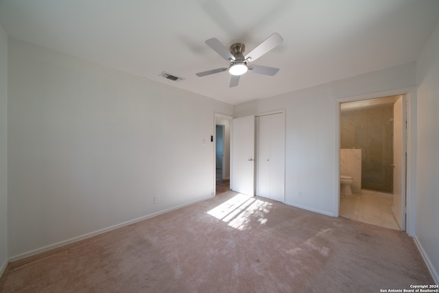 unfurnished bedroom with ceiling fan, ensuite bath, light carpet, and a closet