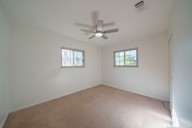 carpeted empty room with ceiling fan and a wealth of natural light