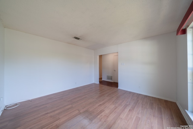 unfurnished room with a textured ceiling and light hardwood / wood-style floors