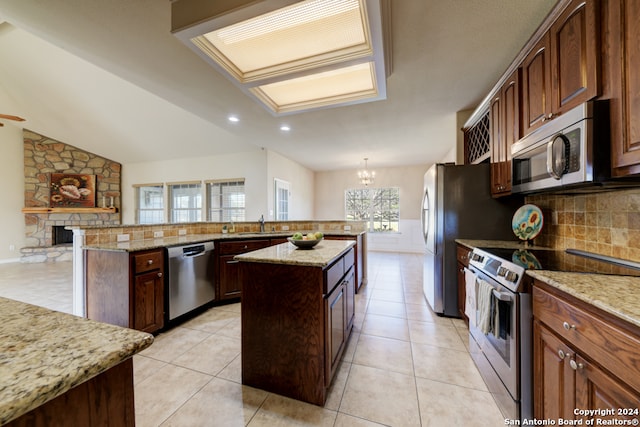 kitchen featuring a wealth of natural light, a kitchen island, appliances with stainless steel finishes, and vaulted ceiling