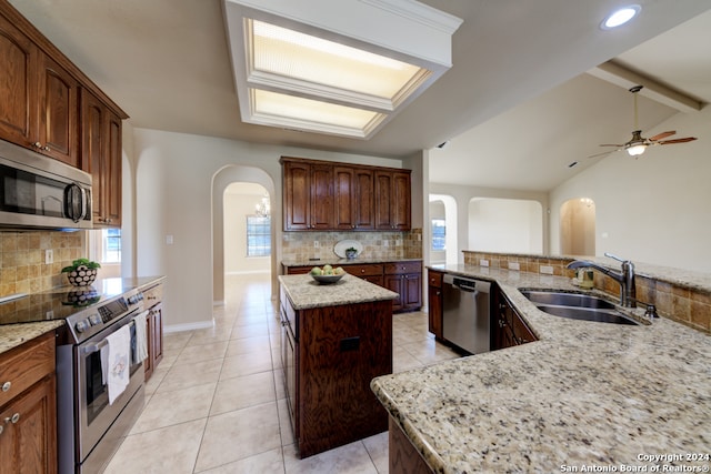 kitchen featuring a center island, sink, stainless steel appliances, lofted ceiling with beams, and decorative backsplash