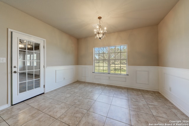 tiled empty room with a notable chandelier