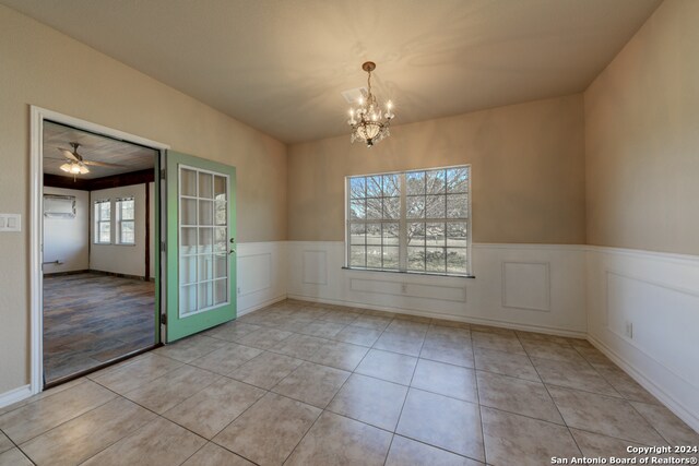 unfurnished dining area featuring ceiling fan with notable chandelier and light tile patterned flooring