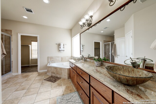 bathroom featuring tile patterned flooring, vanity, shower with separate bathtub, and a chandelier