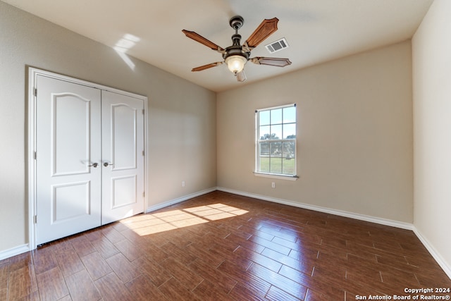 unfurnished bedroom featuring a closet, dark wood-type flooring, and ceiling fan