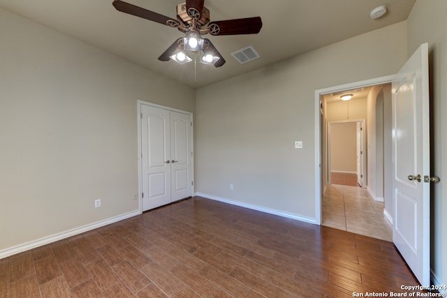 unfurnished bedroom with hardwood / wood-style floors, ceiling fan, and a closet