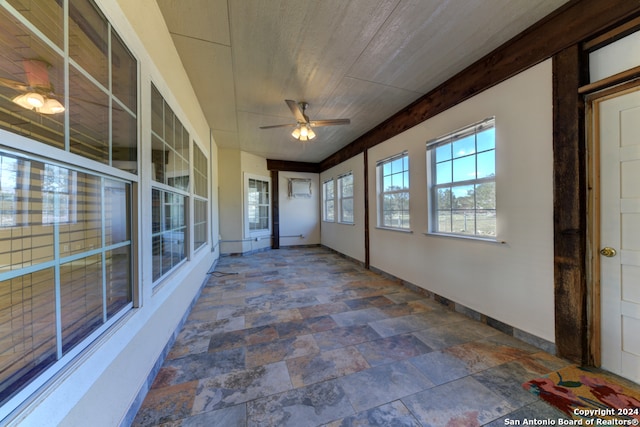 unfurnished sunroom with ceiling fan