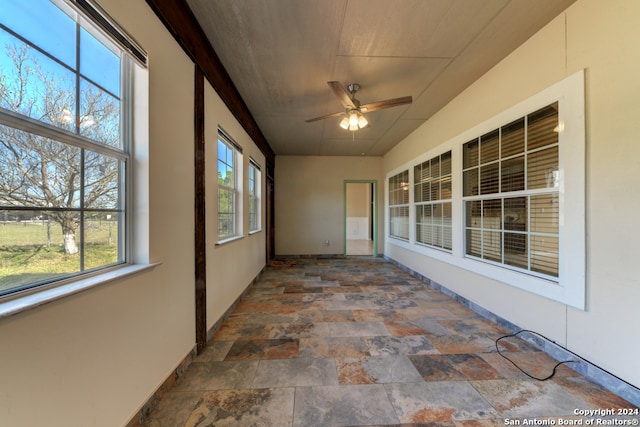 unfurnished sunroom featuring a wealth of natural light and ceiling fan