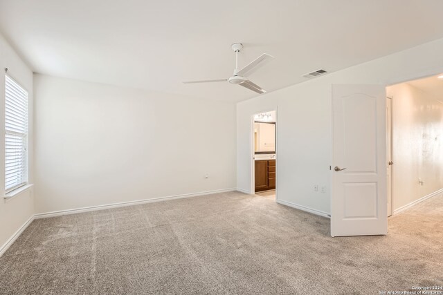 empty room with ceiling fan, light colored carpet, and a wealth of natural light